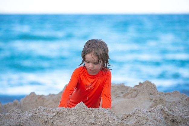 Child making sand castle at beach on sea