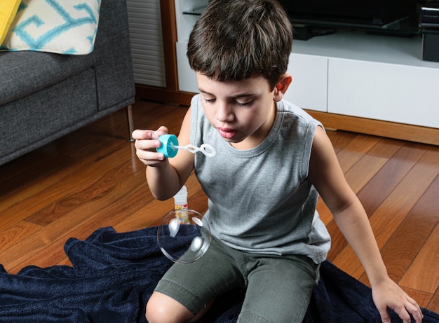 Bambino che fa la bolla di sapone a casa