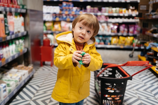 Child in the market with a grocery cart buys a ball