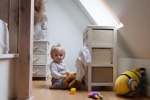 Child in messy room toddler one year old baby boy with funny
facial expression playing in bedroom