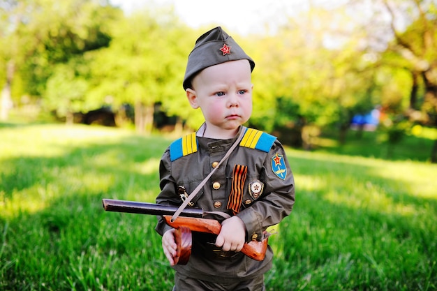 Child in military uniform against nature background