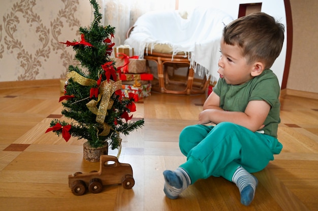 Child in the morning near the Christmas tree. High quality photo