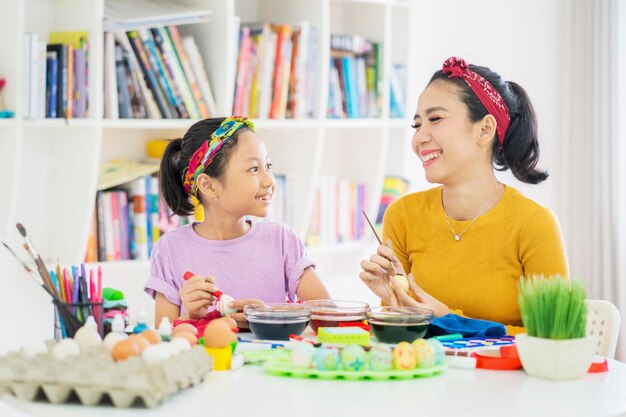 Child and mother decorating Easter eggs with dye