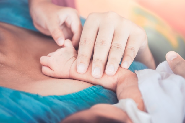 Bambino e madre che tengono la mano minuscola del neonato con amore