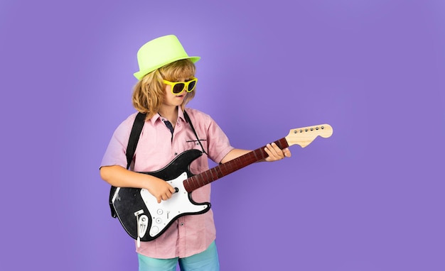 Child musician playing the guitar like a rockstar on studio background