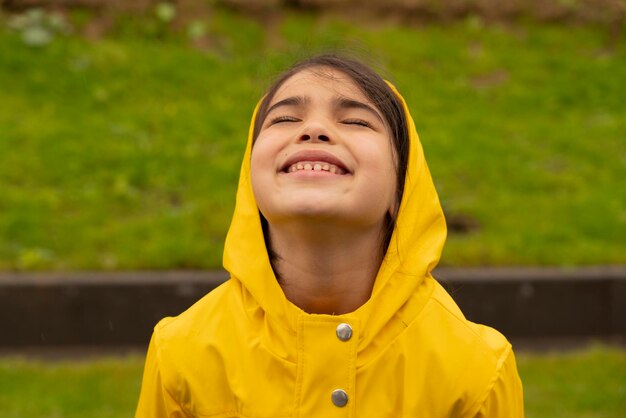 Child in nature under sun with a yellow rain coat