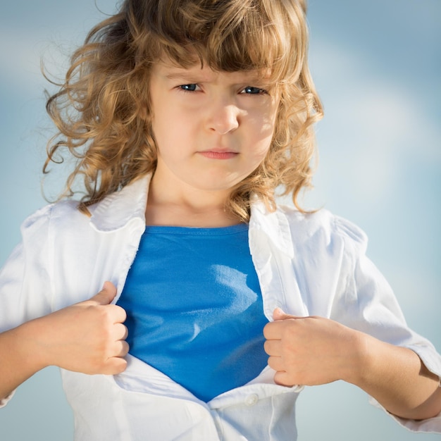 Child opening his shirt like a superhero girl power and feminism concept