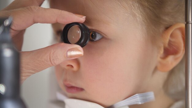 Child in ophthalmology clinic - optometrist diagnosis little blonde girl, close up