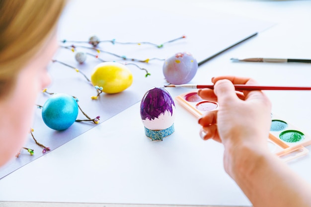 A child painting easter eggs on a table