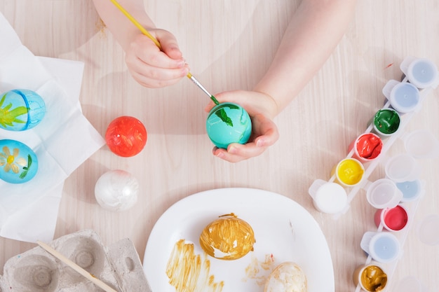 child paints Easter eggs while sitting at the table