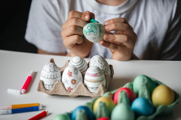 Child paints eggs with different colors