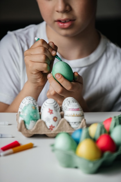 Child paints eggs with different colors