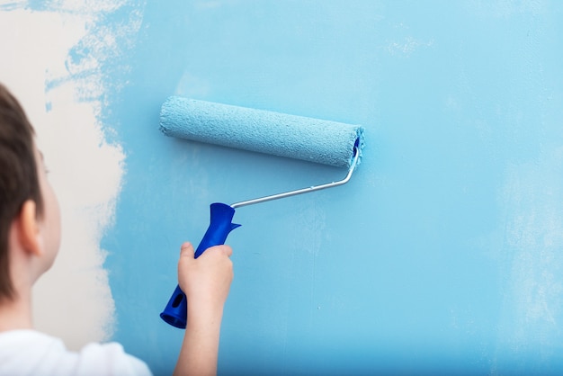 child paints with roller a wall blue The concept of world peace Blue sky overhead