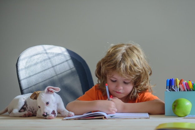 学校の宿題をしている子犬と一緒に家で遊んでいる子供とペットの犬