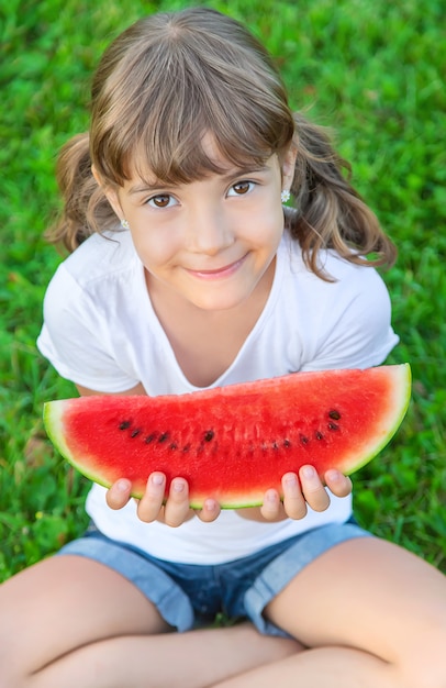 A child on a picnic eats a watermelon