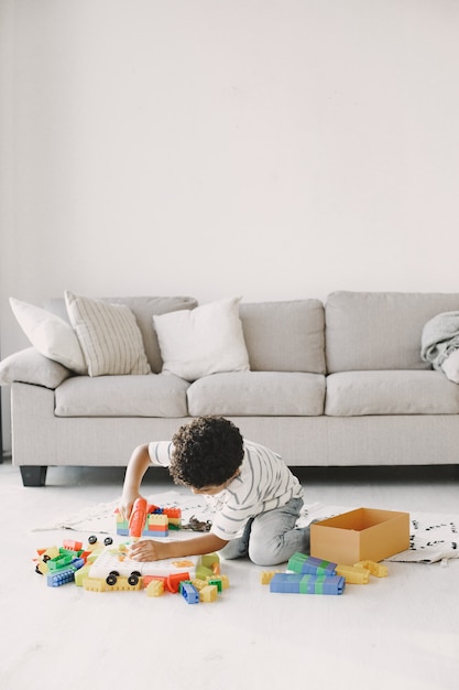 Il bambino gioca con i giochi sul pavimento. il bambino africano compone un costruttore. capelli ricci in un ragazzo.