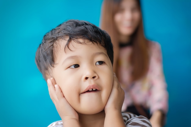 写真 子供は青い背景にママと遊ぶ。