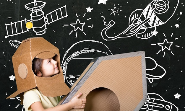 Child playing astronaut using cardboard box as helmet