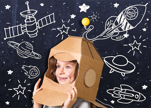 Photo child playing astronaut using cardboard box as