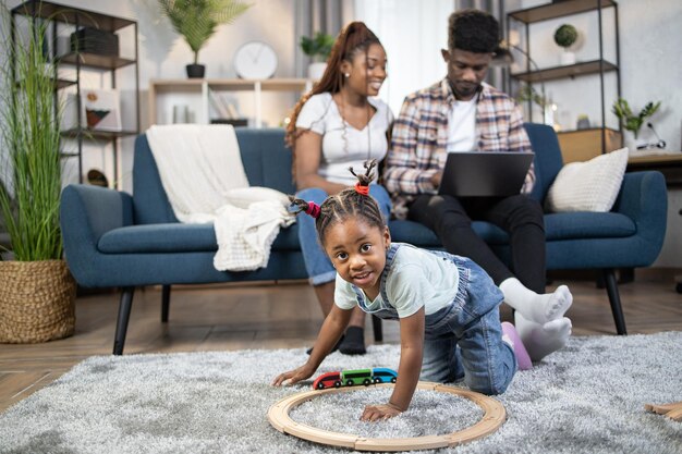 Child playing on floor while parents using laptop on couch