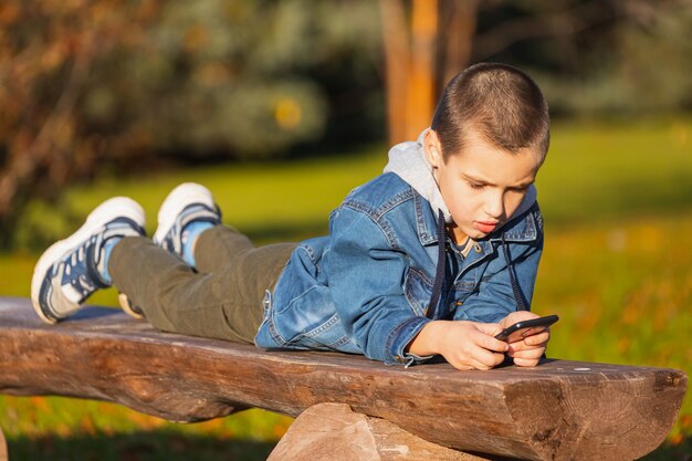 公園でスマートフォンでゲームをしている子供