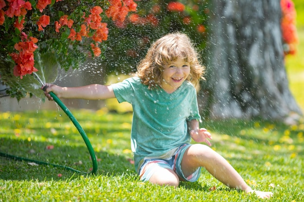 Child playing in garden pours from the hose makes a rain happy childhood concept