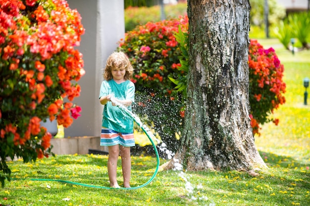 Child playing in garden pours from the hose makes a rain happy childhood concept