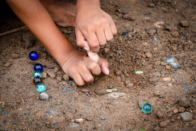 土の上でガラス玉を遊んでいる子供