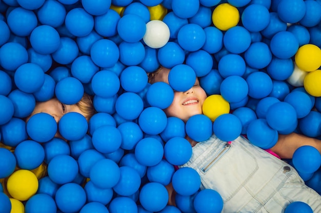 写真 ボールピットで遊ぶ子供子供のためのカラフルなおもちゃ幼稚園または就学前のプレイルームデイケアの幼児の子供屋内遊び場子供のためのボールプールアクティブな未就学児のための誕生日パーティー