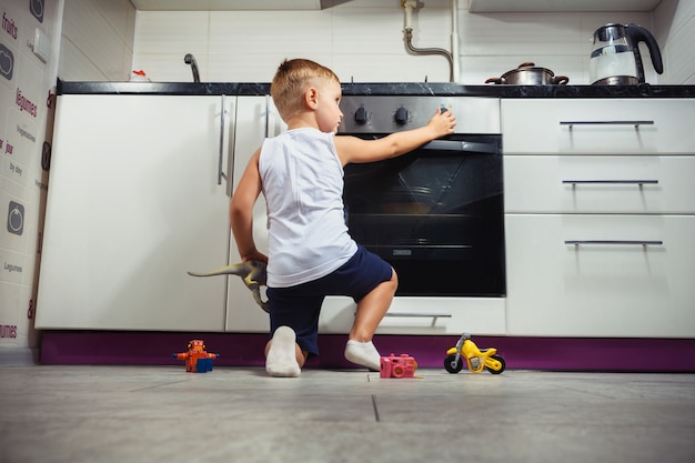 Child playing in the kitchen with a gas stove.