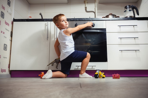 Bambino che gioca in cucina con una stufa a gas.