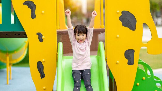 Child playing on outdoor playground kids play on school or kindergarten yard active kid on colorful slide and swing healthy summer activity for children little boy climbing outdoors