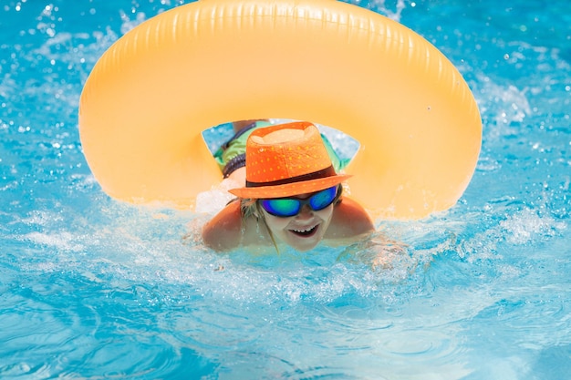 Child playing in swimming pool Kids holidays and vacation concept Summer kids cocktail Happy little boy with inflatable ring in swimming pool