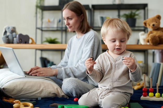 Child playing toys with his working mom