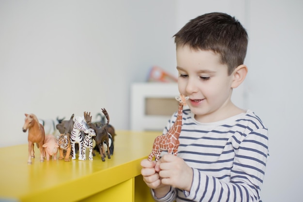 Child playing with animal figurines toys