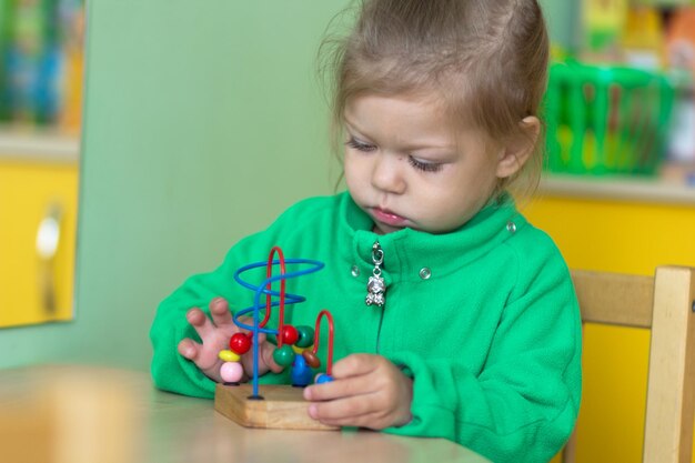 幼稚園でビーズ迷路のおもちゃで遊ぶ子供