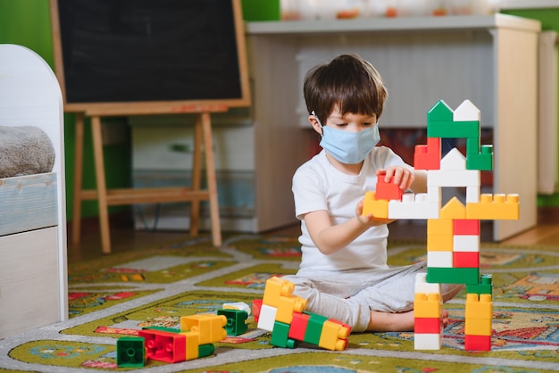 カラフルなおもちゃのブロックで遊ぶ子。少年が自宅やデイケアでタワーを構築します。幼児向け教育玩具