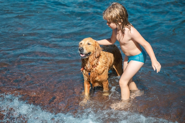 Child playing with dog in sea water on beach