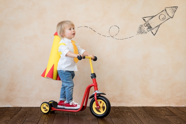 Child playing with paper rocket indoor