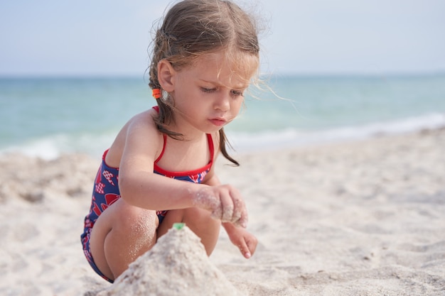 해변에서 모래를 가지고 노는 아이