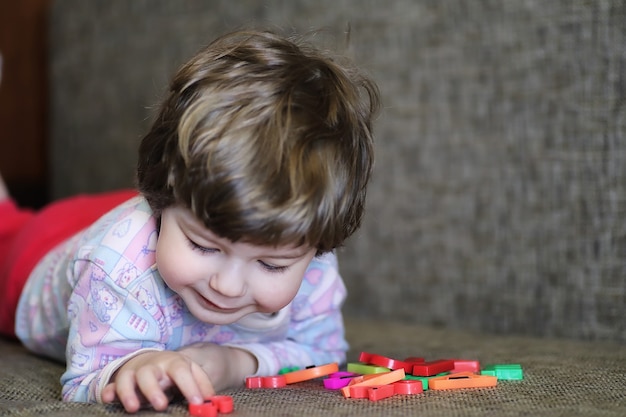 Child playing with small toys on the couch in the room