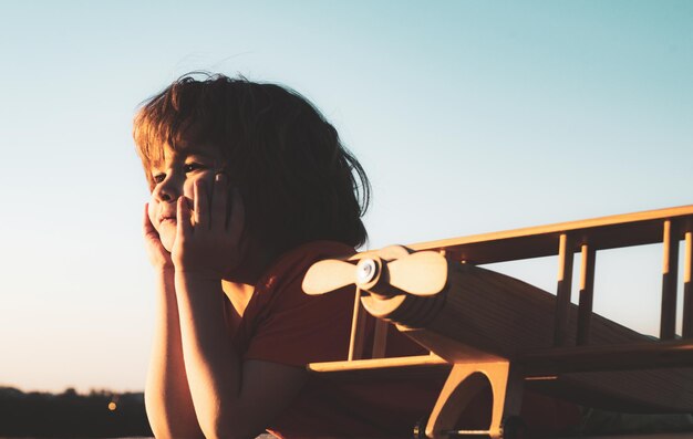 Child playing with toy airplane at sunset dreaming boy with wooden plane child pilot aviator with ai