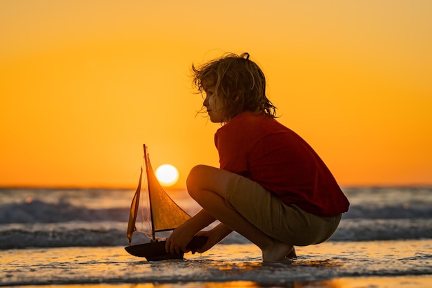 海でおもちゃのボートで遊ぶ子供 海辺での幸せな休日 セーリングを夢見る小さな船員の子供