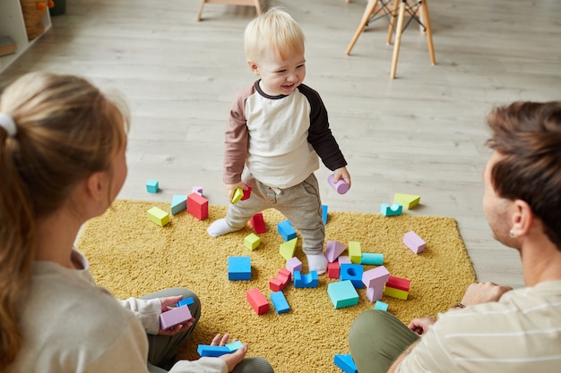 Фото Ребенок играет с игрушками на полу вместе со своими родителями дома