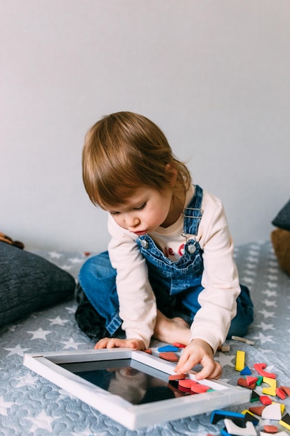 Il bambino gioca a casa un gioco educativo con un puzzle magnetico multicolore