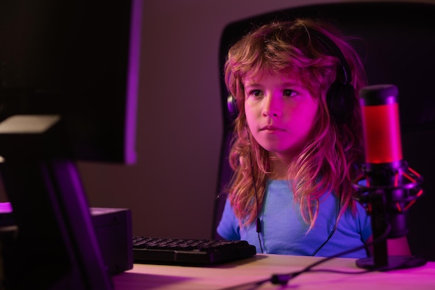 Child plays a video game on the pc computer screen School study online learning concept Gamer play computer games Neon lighting