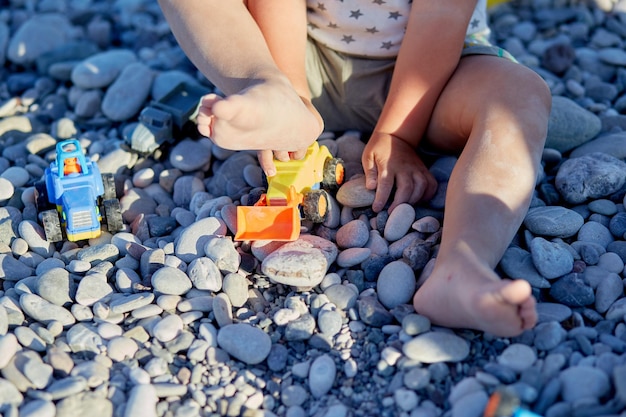 A child plays with toys and pebbles on the beach The concept of recreation play and the development of children39s motor skills High quality photo