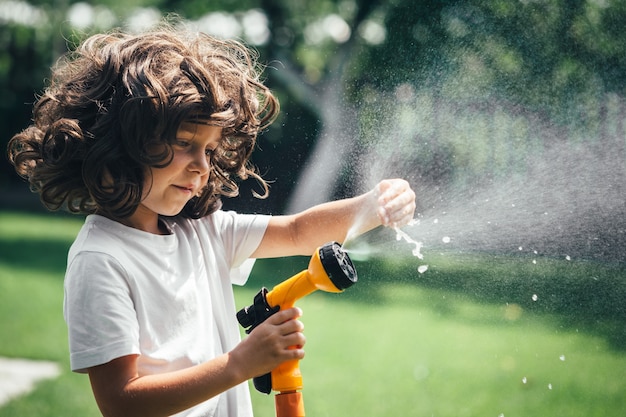 Il bambino gioca con l'acqua nel cortile in giardino