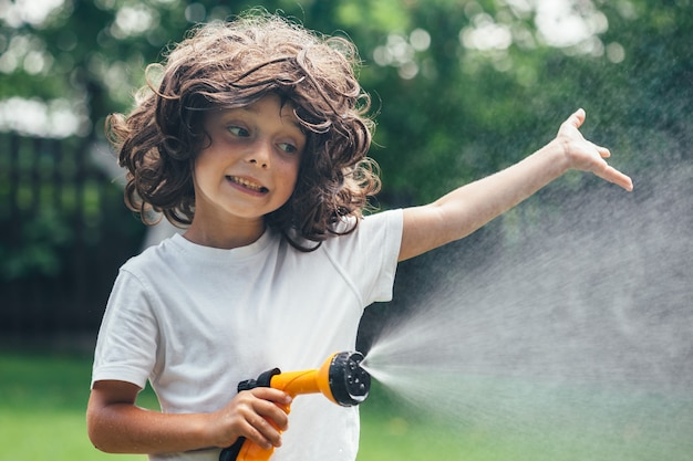 Child plays with water in the backyard in the garden