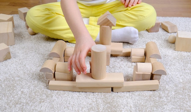 Bambino gioca con cubi di legno sul pavimento